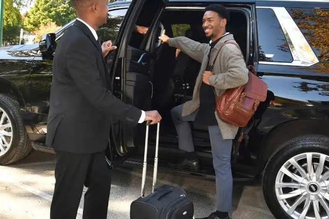 Car service to JFK Airport chauffeur standing beside a private car